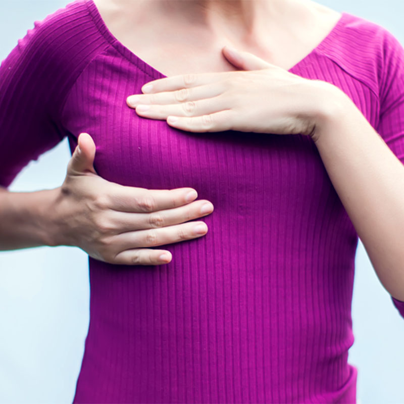 Closeup cropped portrait young woman with breast pain touching chest on white background