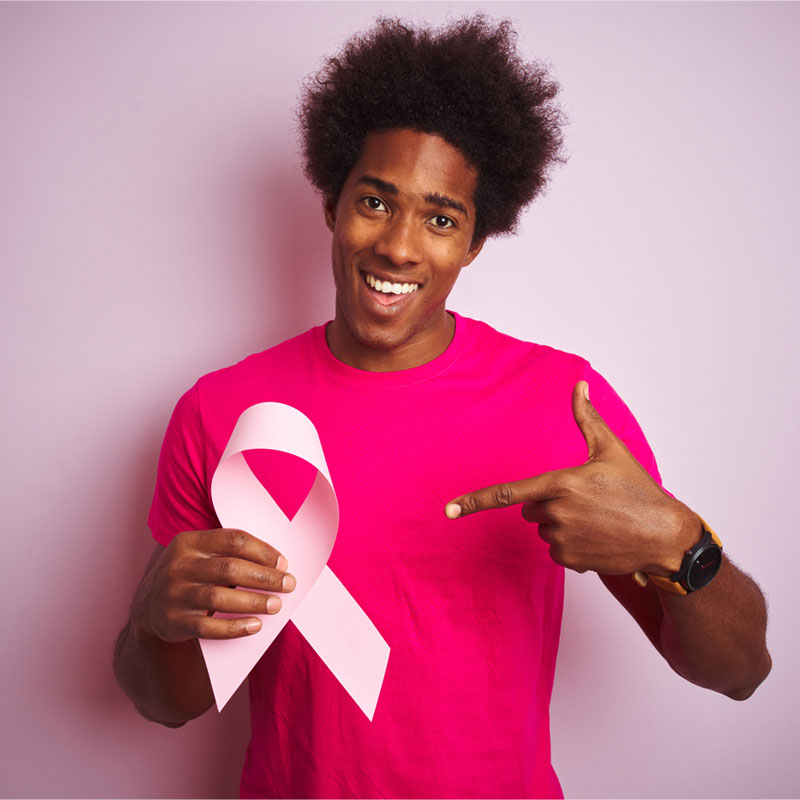 Young african american man holding cancer ribbon standing over isolated pink background very happy pointing with hand and finger